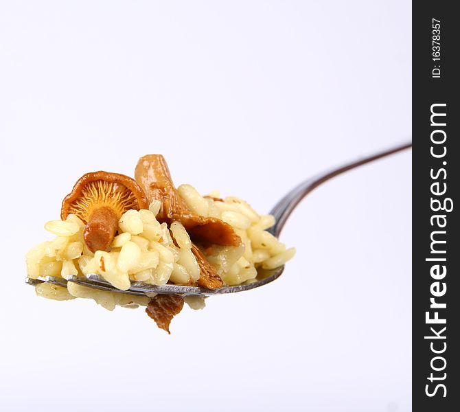 Risotto with mushrooms on a fork on white background