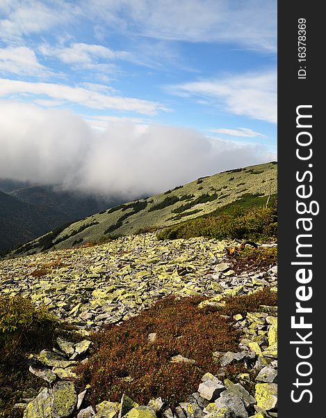 A mountain stone slope in a fog in a landscape with the dark blue sky. A mountain stone slope in a fog in a landscape with the dark blue sky