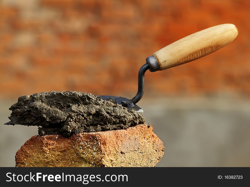 The tool a shovel with concrete on a brick. The tool a shovel with concrete on a brick