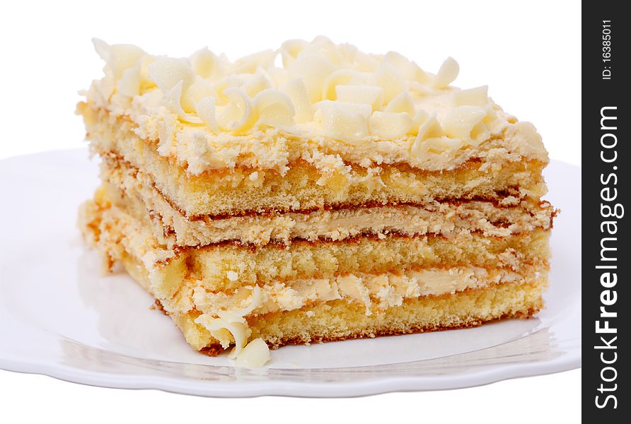 Piece of cake with cream on white plate. Isolated on a white background.