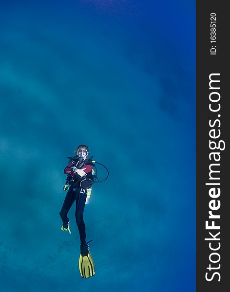 One female scuba diver swimming on her back looking to the surface. One female scuba diver swimming on her back looking to the surface.