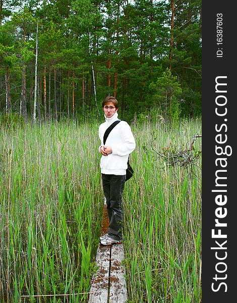 Young scary man is walking through narrow and wet hiking trail on a bog in Engure, Latvia. Young scary man is walking through narrow and wet hiking trail on a bog in Engure, Latvia