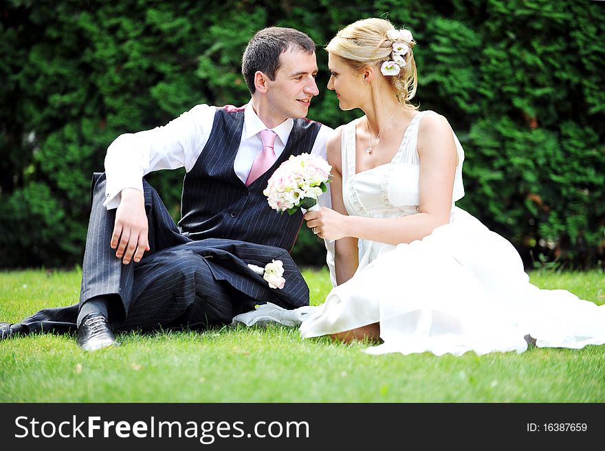 Newly-married couple on green grass in field