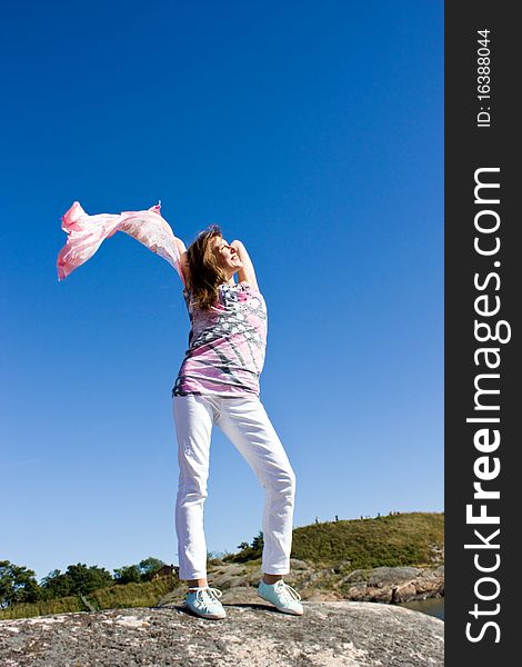 Happy young lady playing with her scarf near the sea, in the wind. Happy young lady playing with her scarf near the sea, in the wind