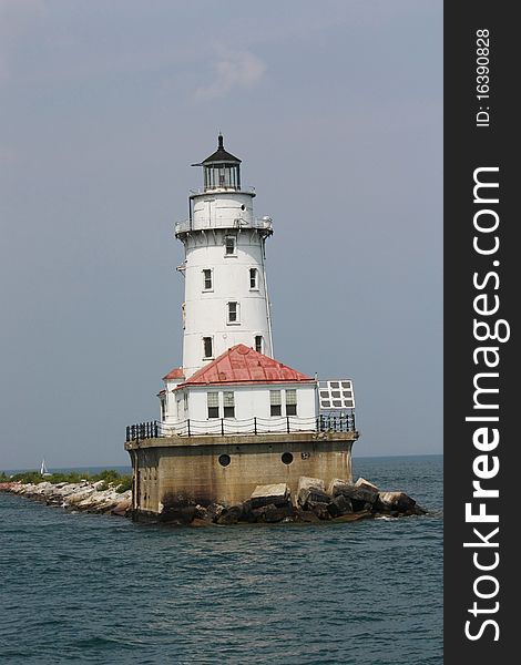 An old white lighthouse set on a lake with blue sky background