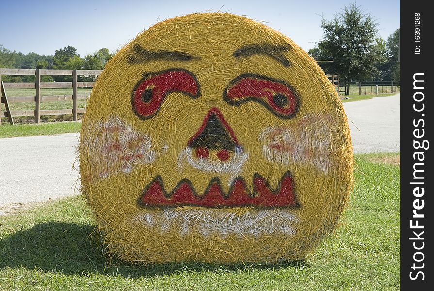 Picture of a pumpkin face painted on side of bale of hale. Picture of a pumpkin face painted on side of bale of hale