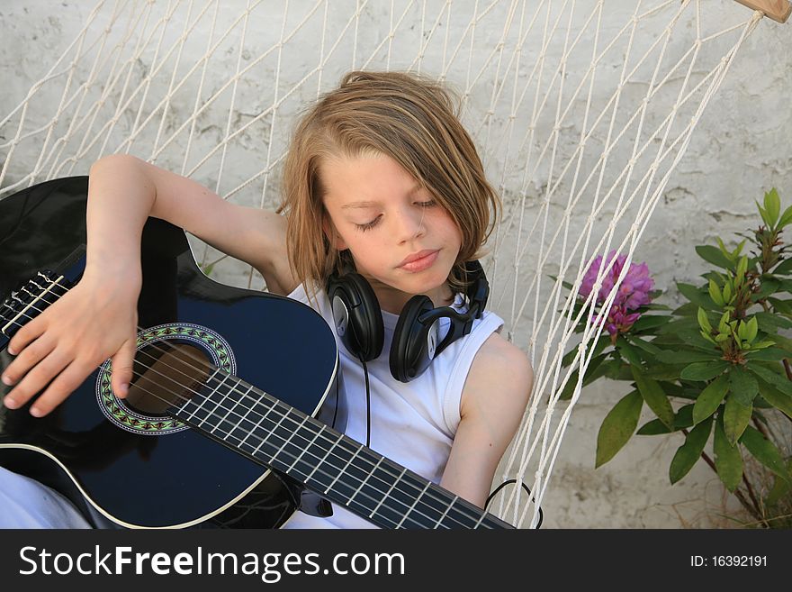 Young boy playing guitar on hammock. Young boy playing guitar on hammock