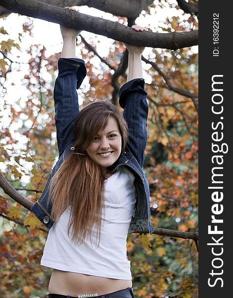 Cheerful girl swinging on a tree in autumn