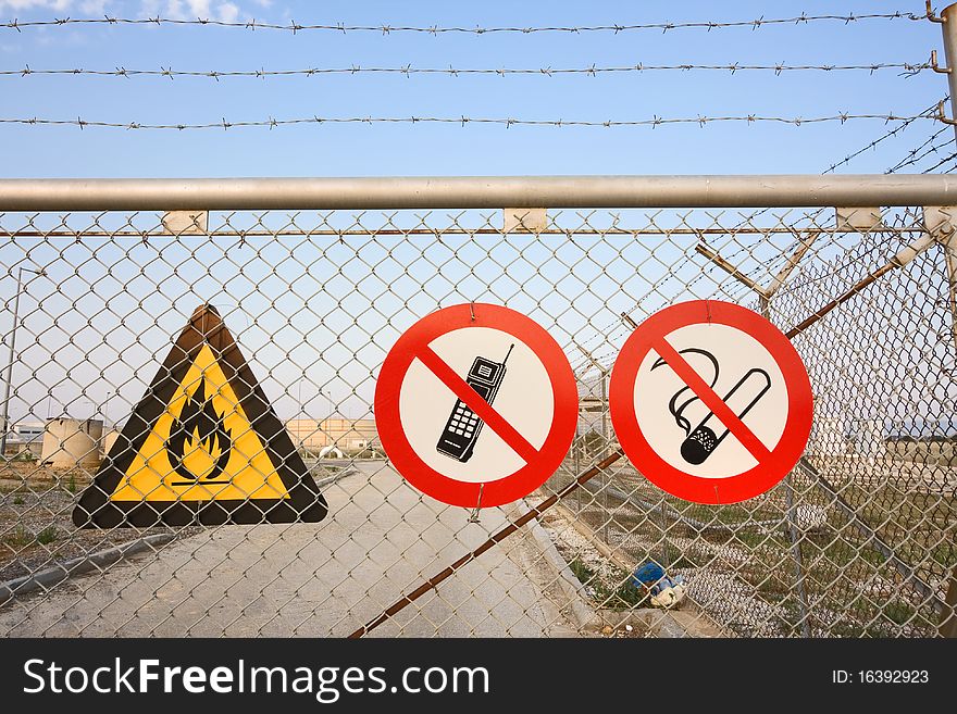 Chainlink and barbed wire fence with warning signs