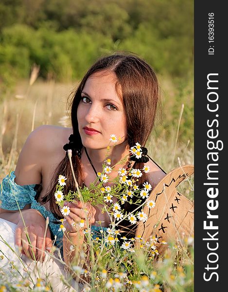 Beautiful woman in a field of flowers chamomile with cowboy hat