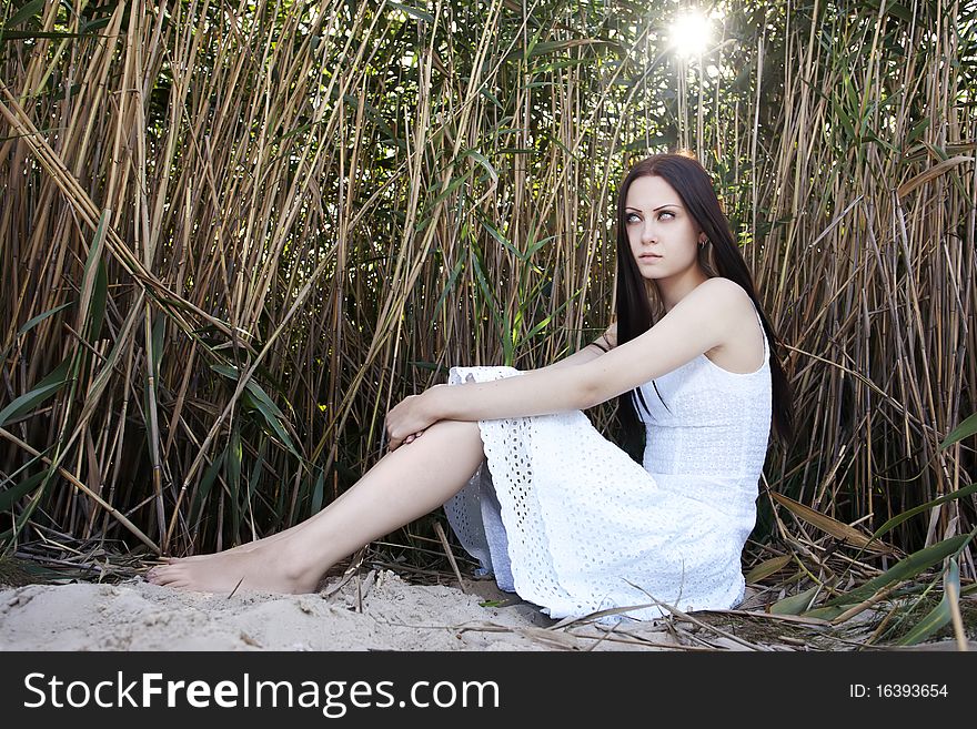 Young beautiful woman in a white dress in a cane