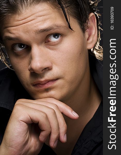 Closeup of a handsome young man thinking against black background