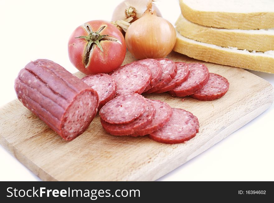 Larded sausage on a chopping board with vegetables. Larded sausage on a chopping board with vegetables