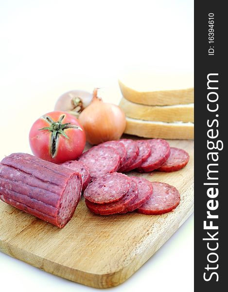 Larded sausage on a chopping board with vegetables. Larded sausage on a chopping board with vegetables