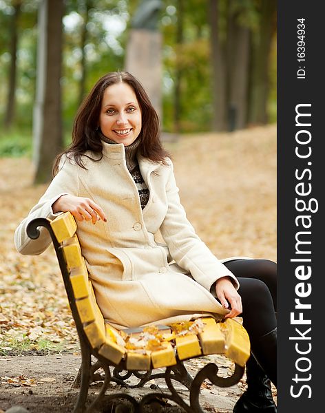 Young woman sitting on bench in autumn park. Young woman sitting on bench in autumn park
