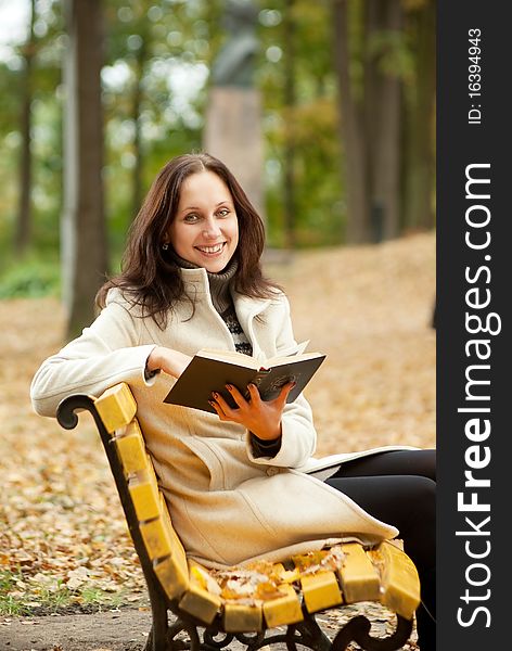 Young woman sitting on bench in autumn