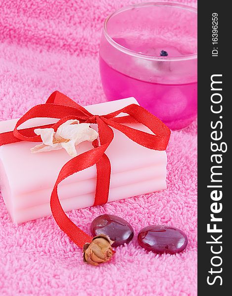 Soap with roses and candle over pink towel