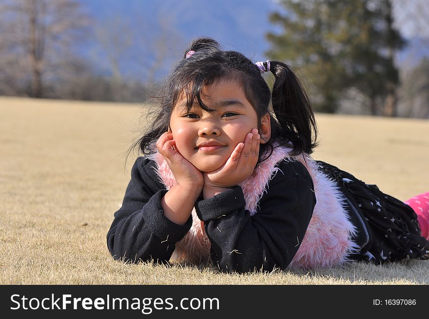 A Malay girl smiles while laying on the spring grass. A Malay girl smiles while laying on the spring grass