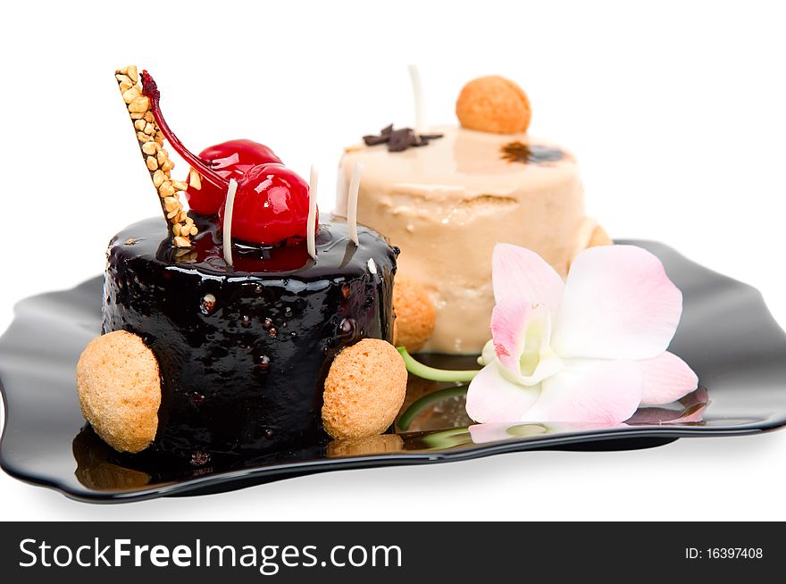 Cake with white and dark chocolate on the black plate isolated on a white background.