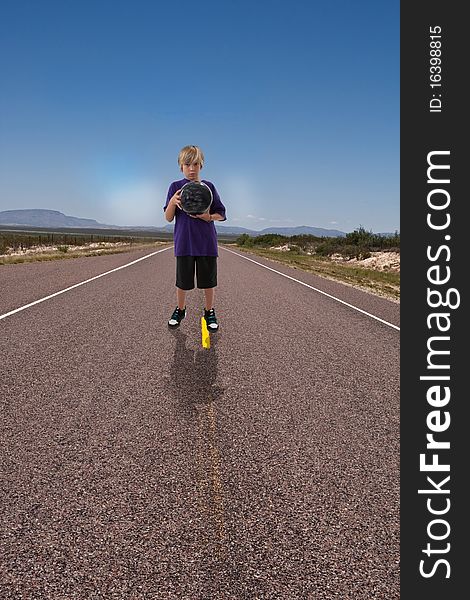 Boy holding bowling ball ready to bowl down deserted highway. Boy holding bowling ball ready to bowl down deserted highway.