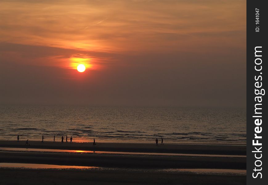 People walking at the beach in the light of a beautiful sunset. People walking at the beach in the light of a beautiful sunset.