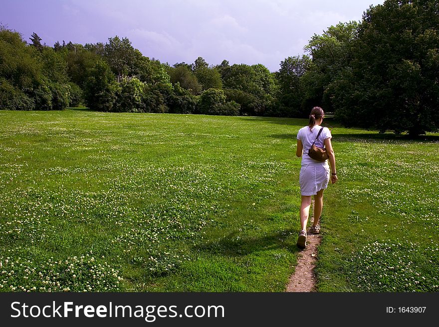 Girl on right side walking on dirt path through green meadow. Girl on right side walking on dirt path through green meadow