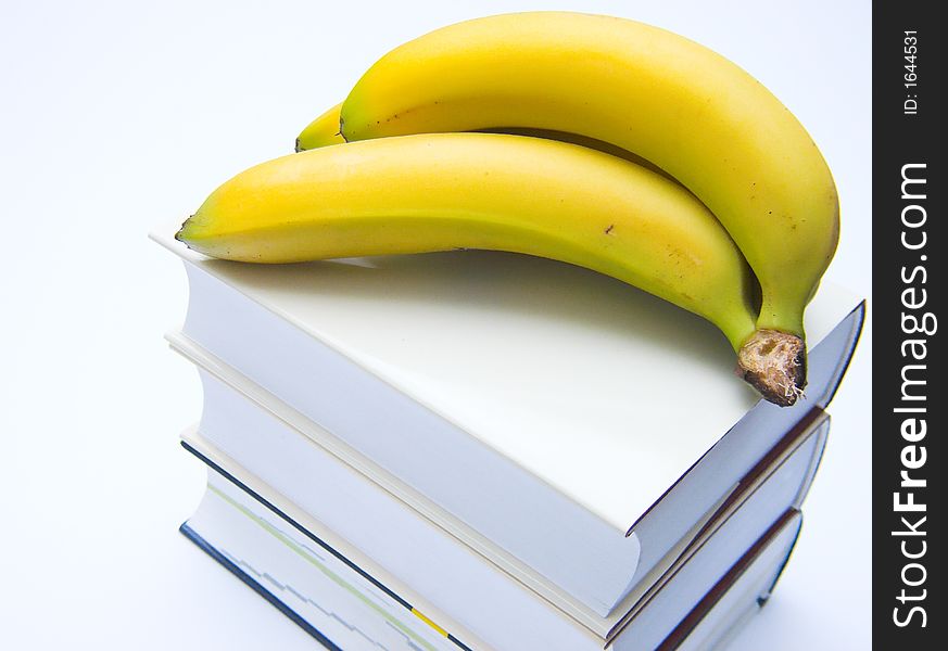 Books and bananas isolated over white background