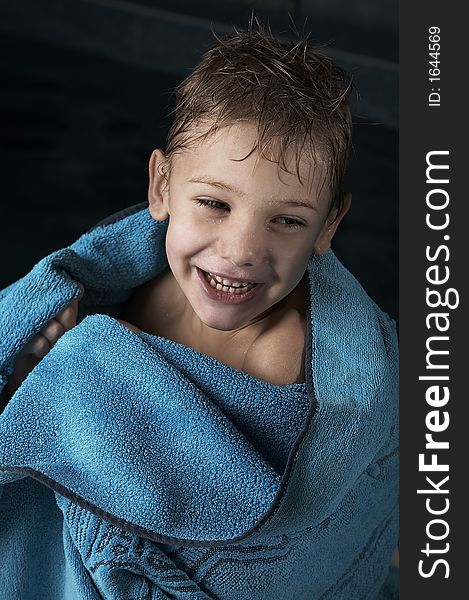 Smiling small boy with blue towel in swimming pool. Smiling small boy with blue towel in swimming pool