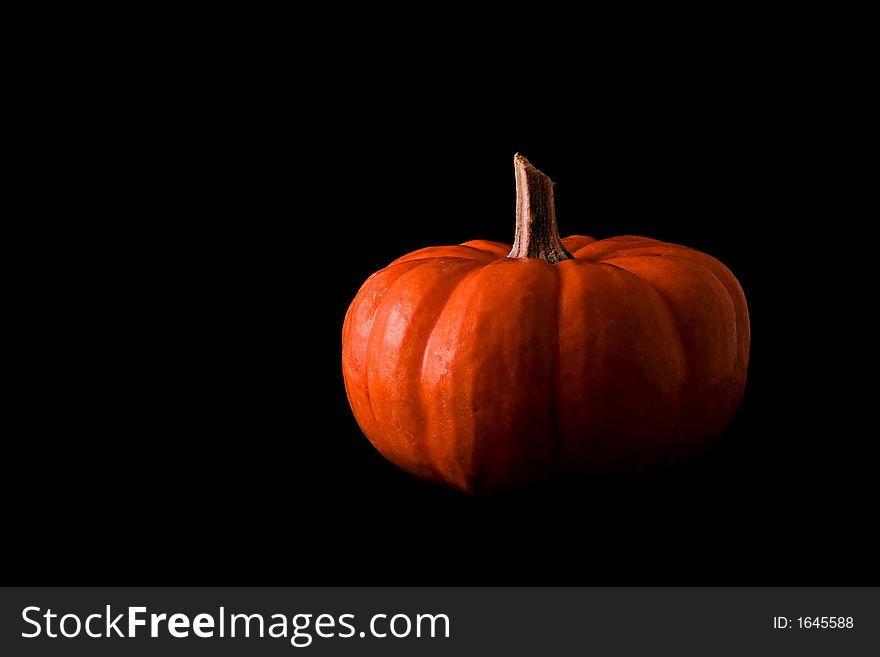 A small pumpkin on a black background. A small pumpkin on a black background