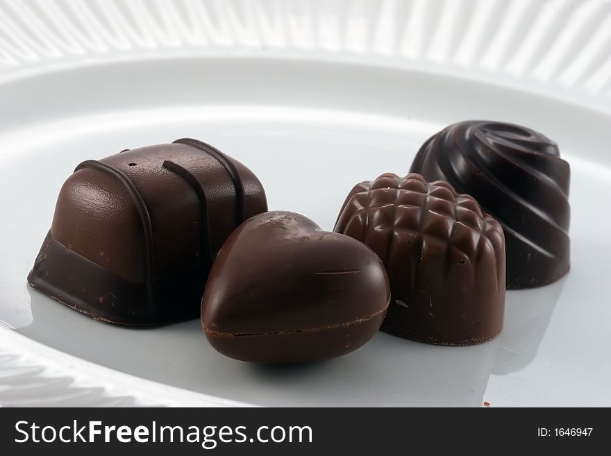 Four dark chocolate candies on a white plate. Four dark chocolate candies on a white plate
