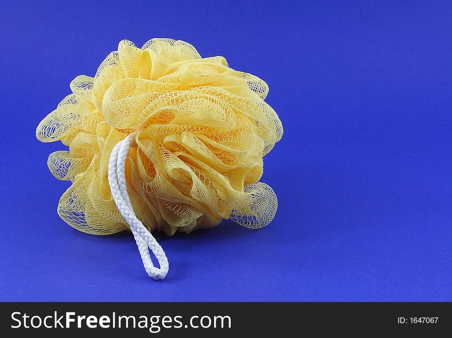 Yellow body sponge with white string on a blue background.