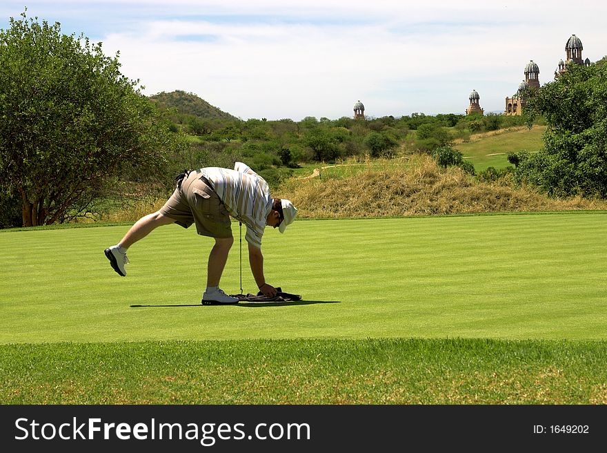 Golfer picking up the towel on the green. Golfer picking up the towel on the green.