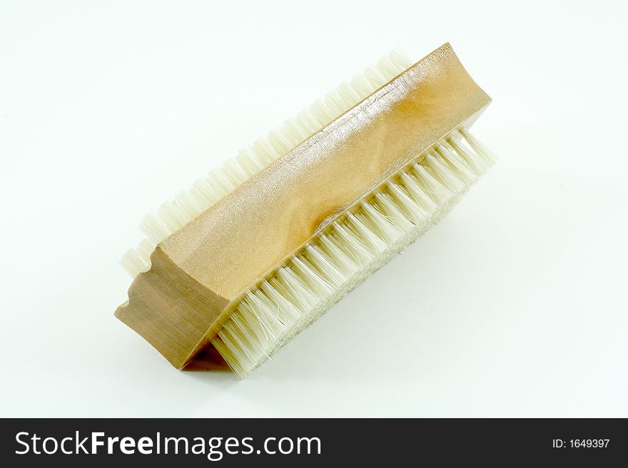 Wooden nail brush with white bristles on a white background.