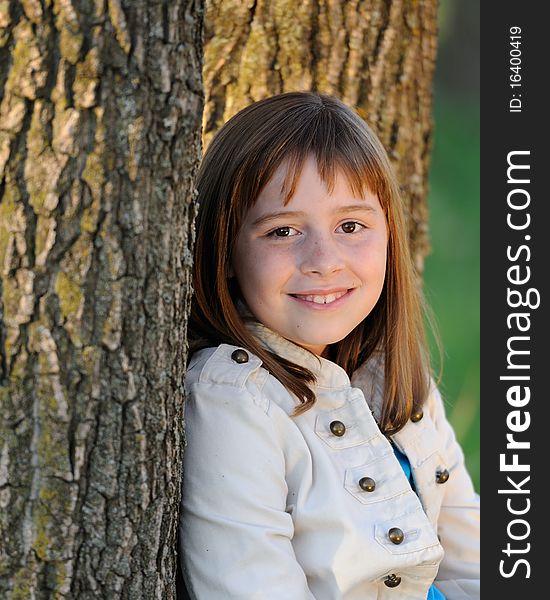 Young caucasian, brunette girl leaning against bark of tree. Young caucasian, brunette girl leaning against bark of tree