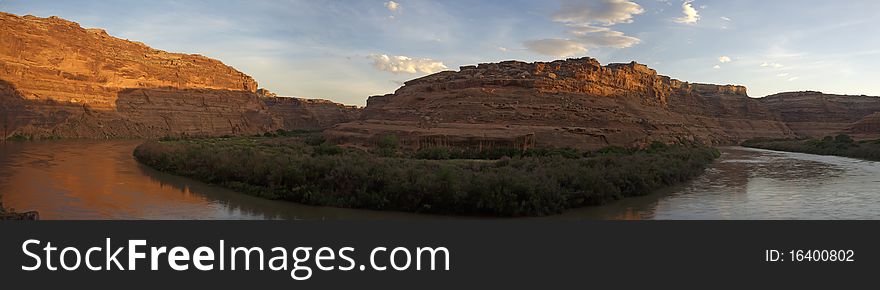 Orange sandstone cliffs reflected in a river at sunset. Orange sandstone cliffs reflected in a river at sunset