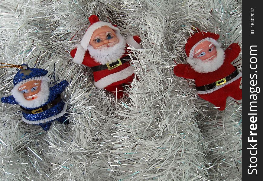 Three toy Santa lie on a silver Christmas garland