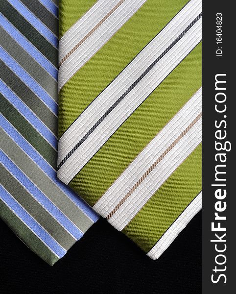 Two ties in green and blue tones, stripe designs on a black background. Two ties in green and blue tones, stripe designs on a black background