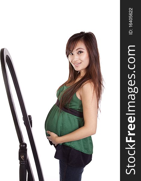 A woman in green is pregnant and standing by a mirror. A woman in green is pregnant and standing by a mirror.