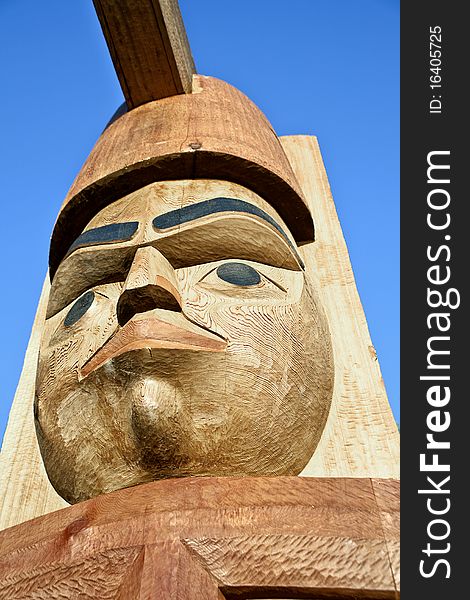 A Native American Totem carved into a cear log with a blue sky in the background. A Native American Totem carved into a cear log with a blue sky in the background