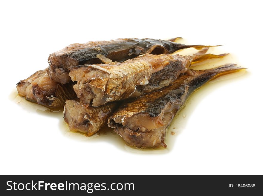 Shows a handful of sprats. Smoked sprats in oil. Oil flows from sprat. Isolated on white background.