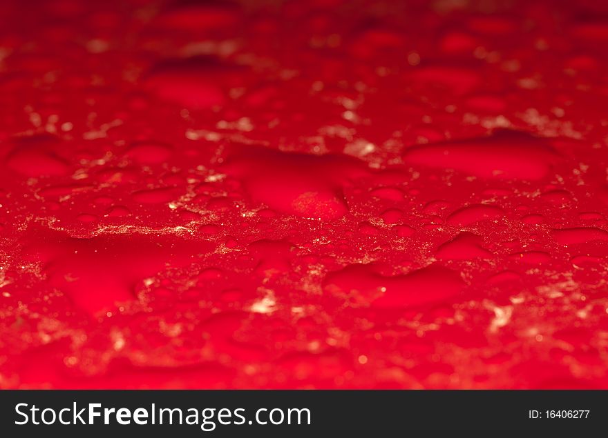 Rain drops on a red surface close up