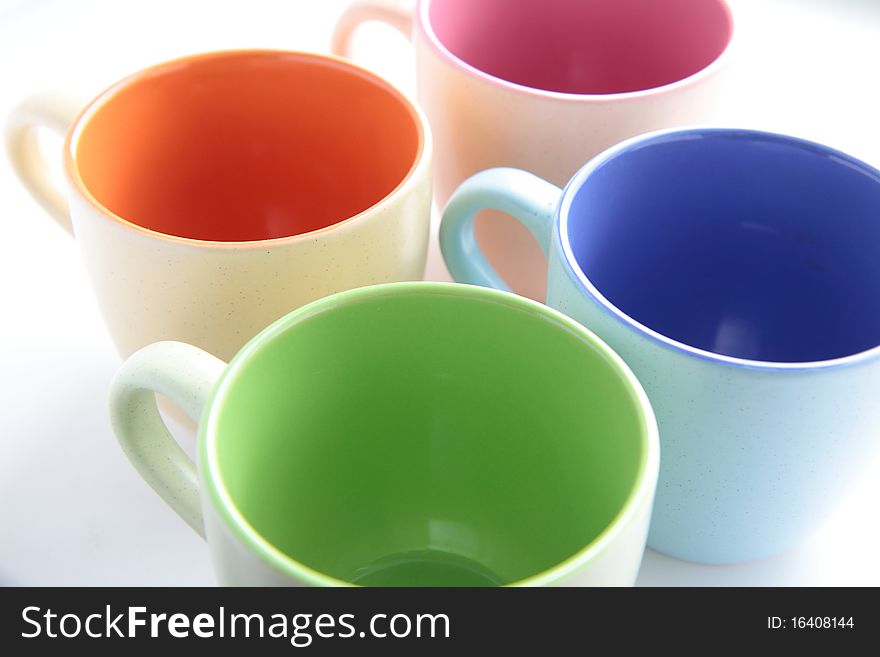 Four empty colored cups on white background