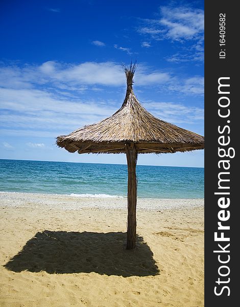 A beach umbrella covered in thatch, on a beach in Romania