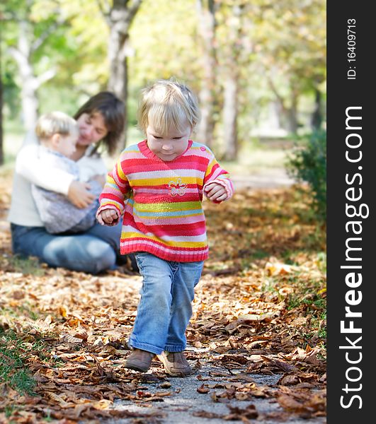 Young girl on mother and brother background in autumn park