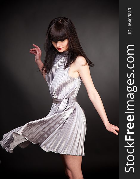 Brunette girl in grey dress, studio isolated shot