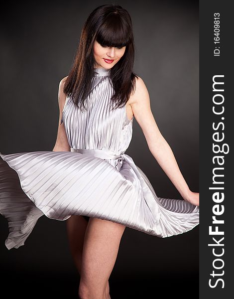 Playing girl in grey dress, isolated in studio shot