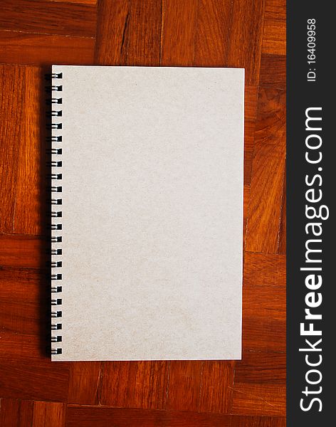 Brown notebook on the parquet wood floor background. Brown notebook on the parquet wood floor background