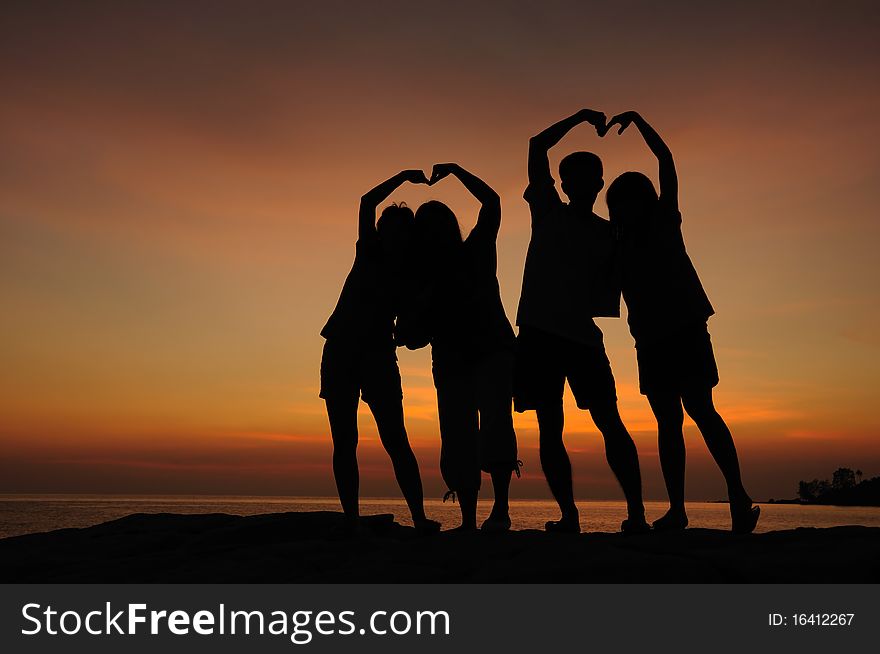 Silhouette of two couple of young people doing heart shape