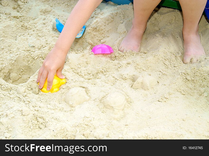 The child does of figure sand on a beach in the summer. The child does of figure sand on a beach in the summer