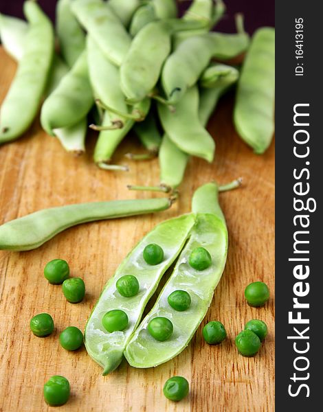 green peas in a wooden bowl and on the board